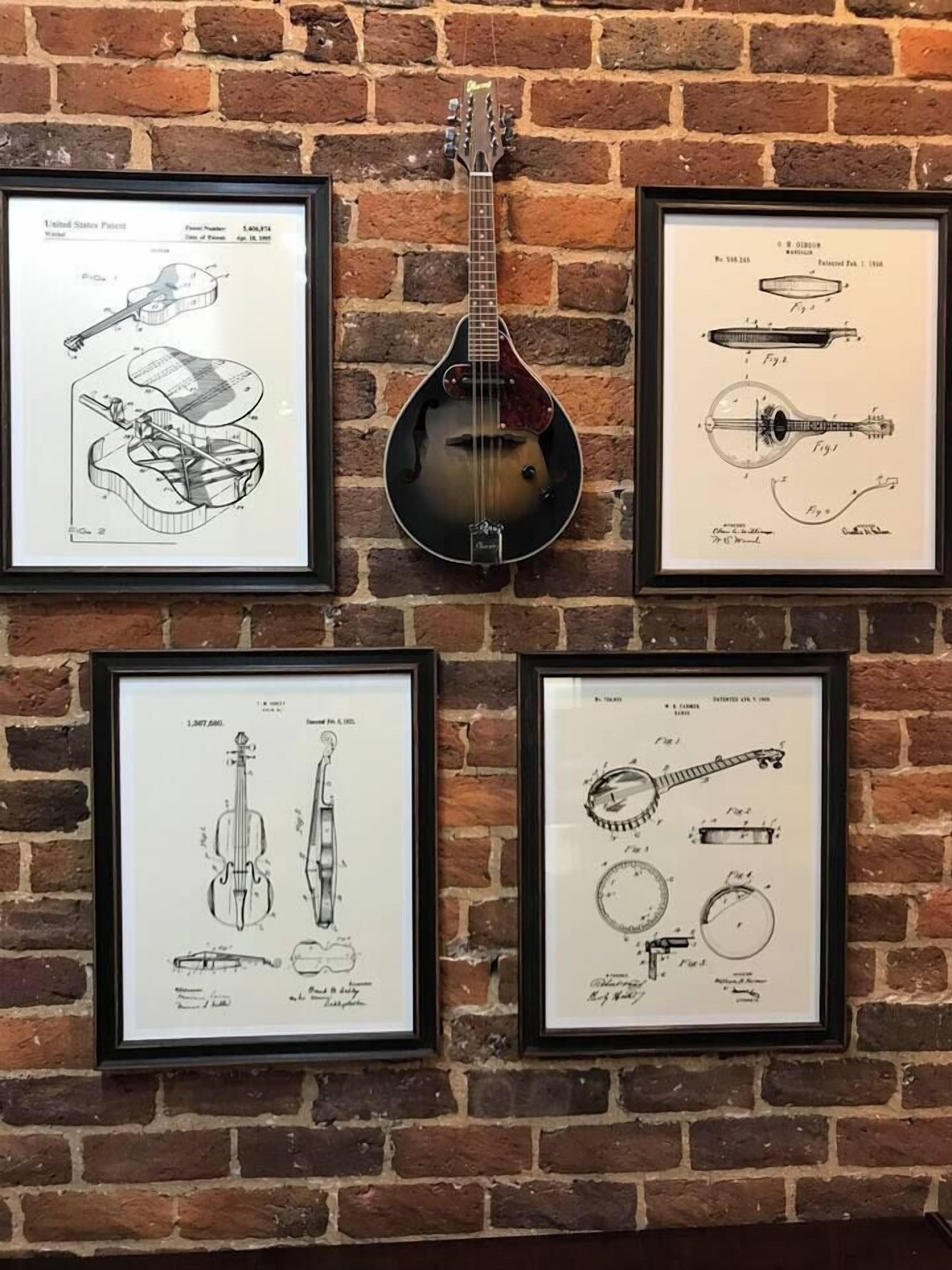 Een muur met vier ingekaderde patenttekeningen van snaarinstrumenten.
