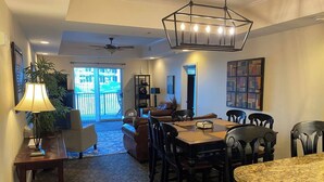 A dining area with a wooden table and chairs, a chandelier, and a view of the outdoors. - Haven of Rest at Bristol Motor Speedway, Unwind (Bluff City)
