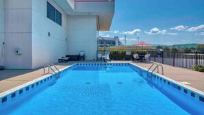 A rectangular swimming pool with a tiled edge, surrounded by a low wall and a paved deck. There are lounge chairs and a table on the deck, and a fence with a sign indicating no diving allowed. - Haven of Rest at Bristol Motor Speedway, Unwind (Bluff City)