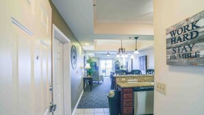 A spacious kitchen with a granite countertop and a built-in dishwasher. There is a dining area with a table and chairs, and a kitchen island with a sink. - Haven of Rest at Bristol Motor Speedway, Unwind (Bluff City)