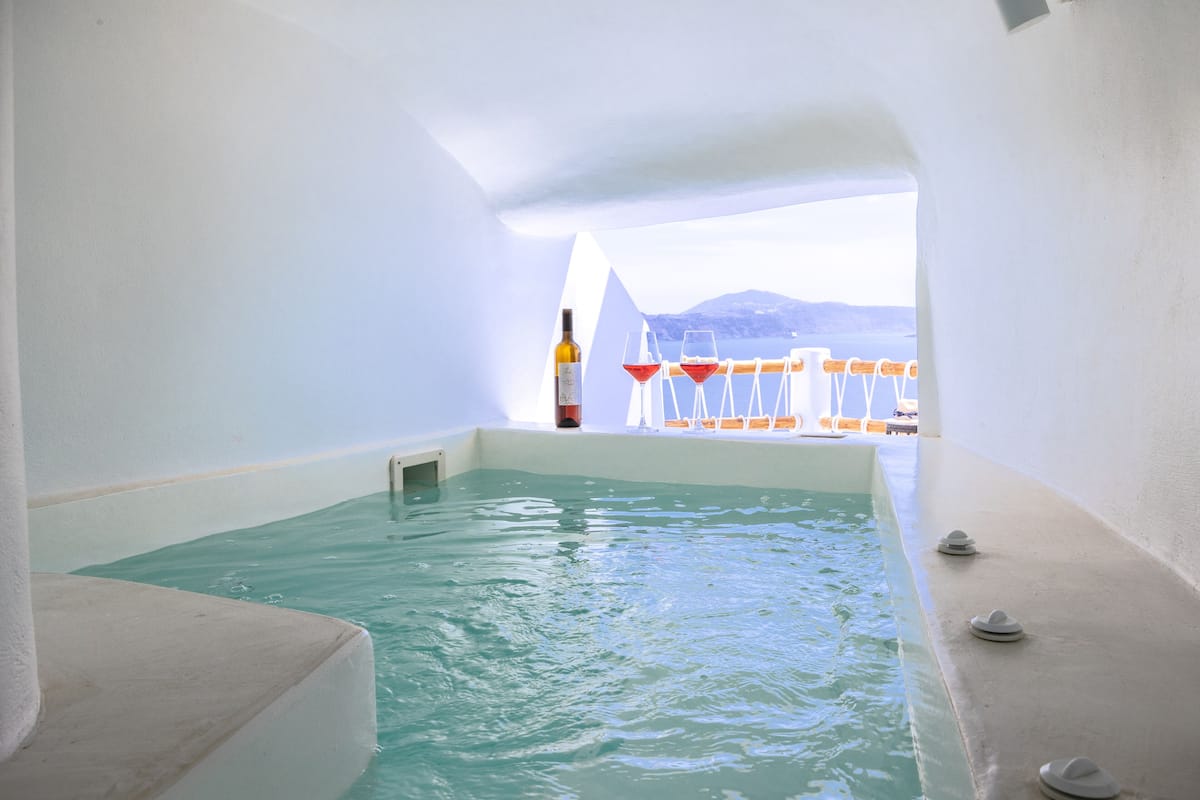 Ein Wellnessbereich mit Whirlpool, einer Weinflasche und Meerblick.