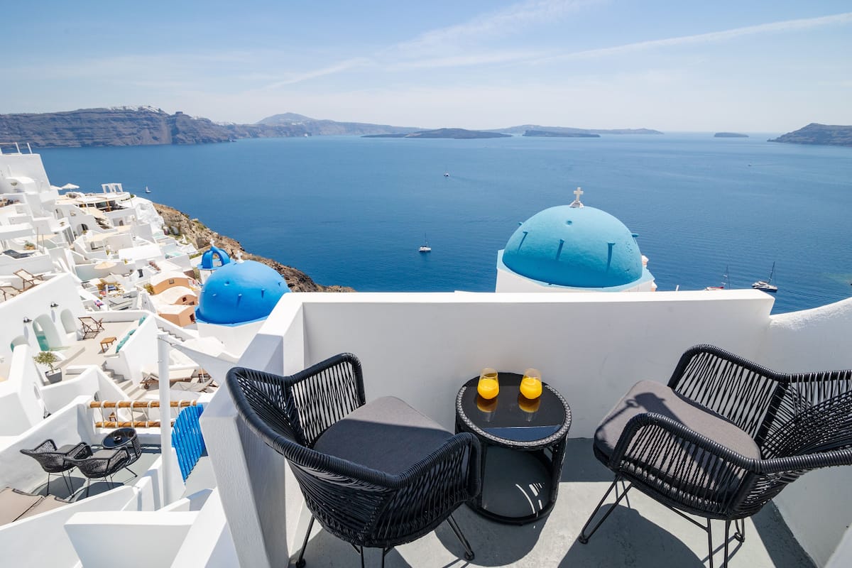Eine Strandterrasse mit weißen Gebäuden, einer blauen Kuppelstruktur und Blick auf das Meer.