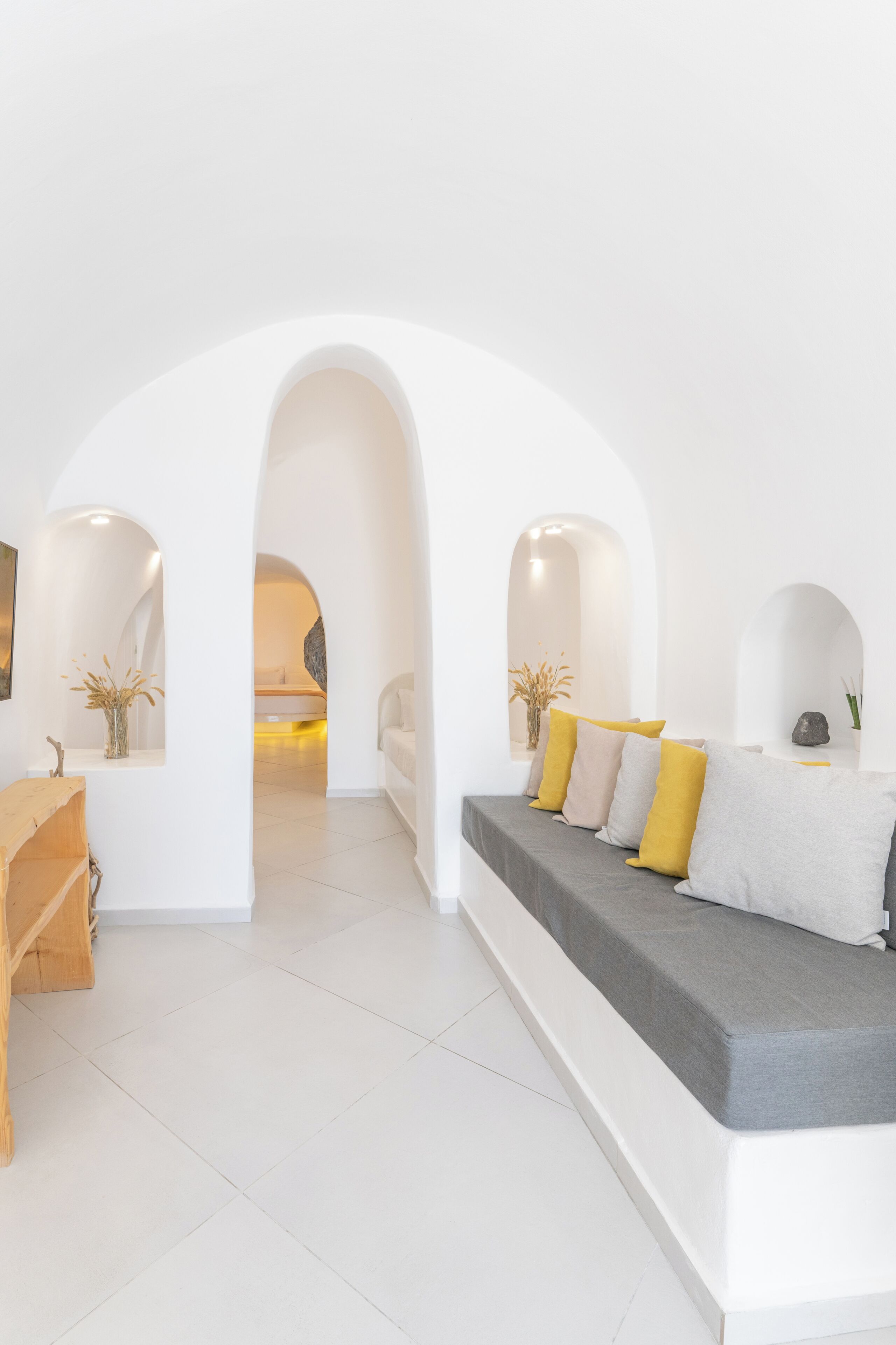 A modern interior with a sofa, archways, and a wooden bench.