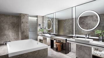 A modern bathroom with a large bathtub, two sinks, and a large mirror with a circular light.