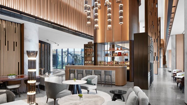 A modern bar area with seating and a bar counter, featuring a mix of round and square tables, and a variety of chairs. - JW Marriott Shanghai Fengxian (Shanghai)