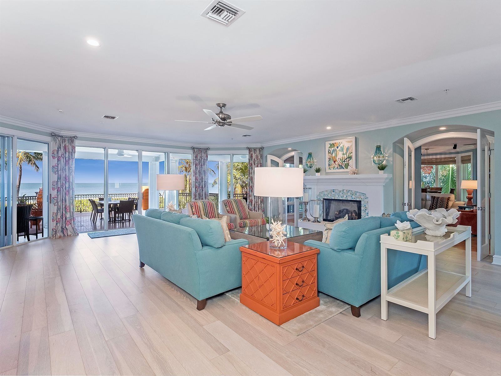 A spacious living room with a large window overlooking the ocean, a fireplace, and a dining area with a view.