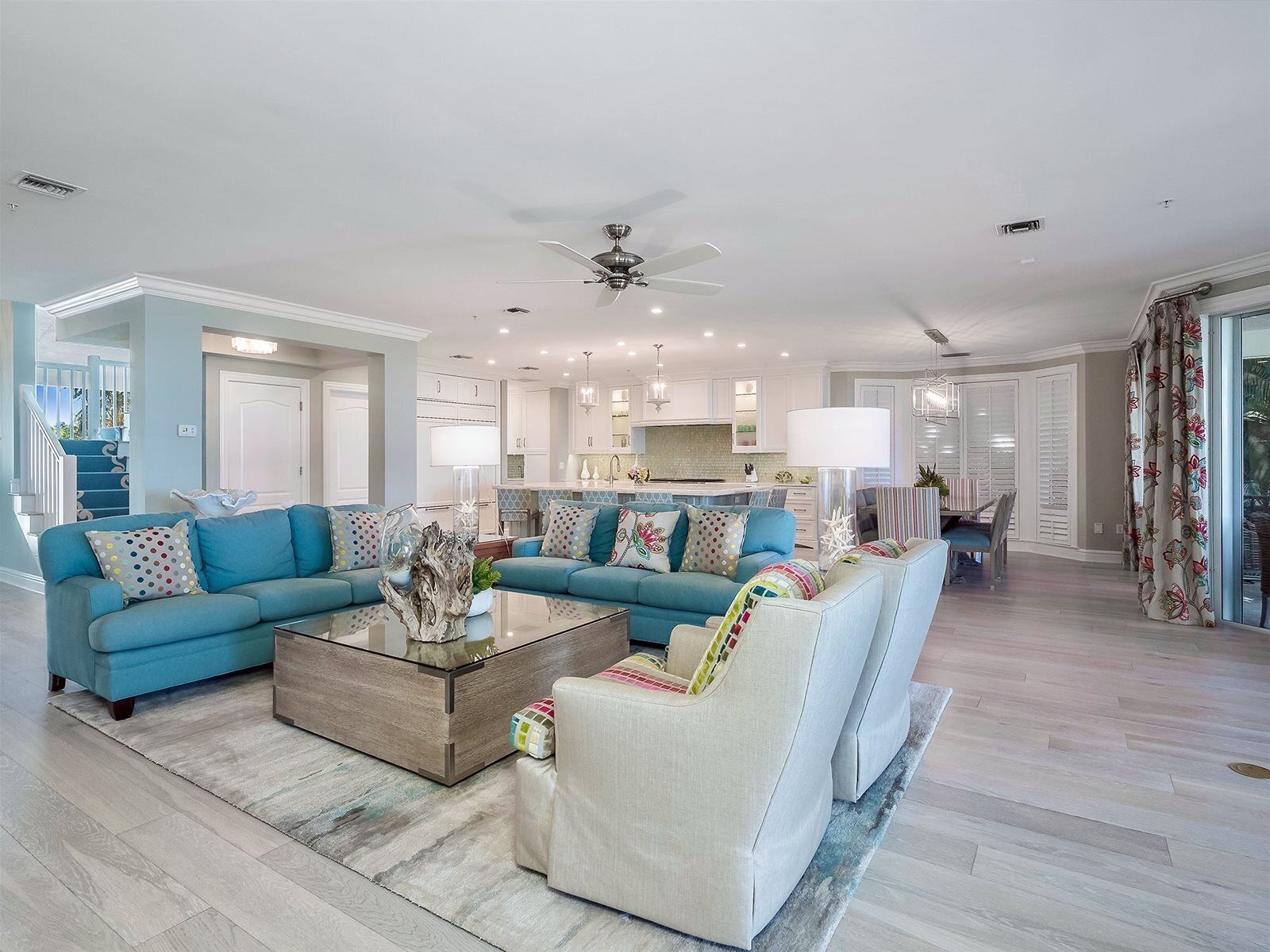 A spacious living room with a large sectional sofa, a coffee table, and a dining area with a chandelier.