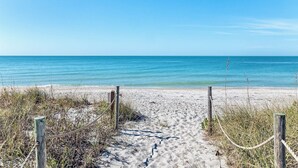 En sandstrand med et træværn, der fører ned til vandet.