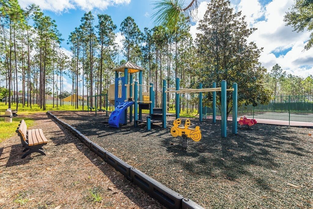 Ein Spielplatz mit Rutsche, Klettergerüsten und einer Sitzbank.
