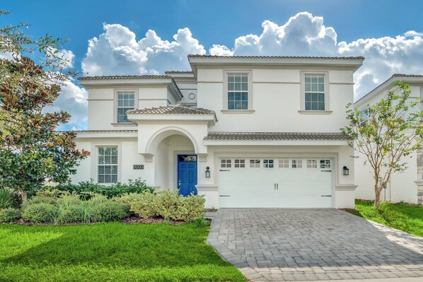A two-story house with a white exterior, a blue door, and a white garage.