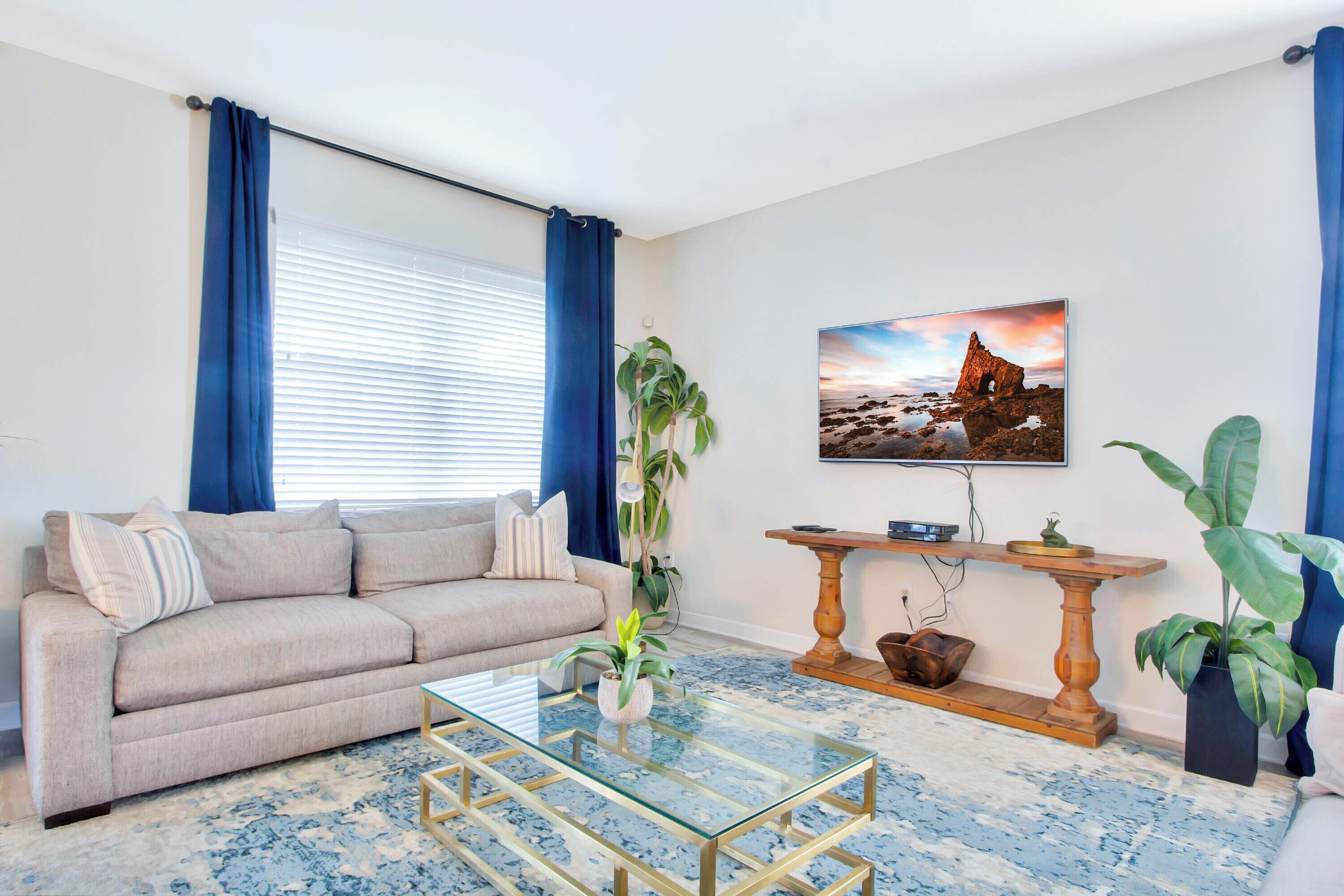 Een woonkamer met een bank, salontafel en planten.