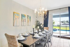 Ein Essbereich mit einem langen Tisch, der für eine Mahlzeit gedeckt ist, einer Kandelaber und Kunstwerken an der Wand.