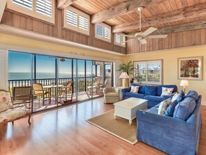A spacious living room with a large sliding glass door leading to a balcony overlooking the ocean. - Shorewood Condos by Dream Vacation Rentals (Sanibel)