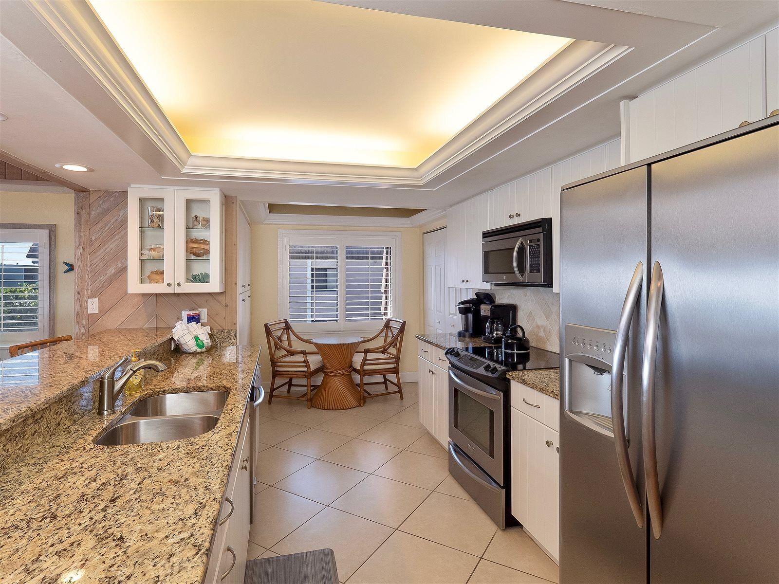 Una cocina moderna con encimeras de granito, electrodomésticos de acero inoxidable y un comedor con mesa y sillas de madera.