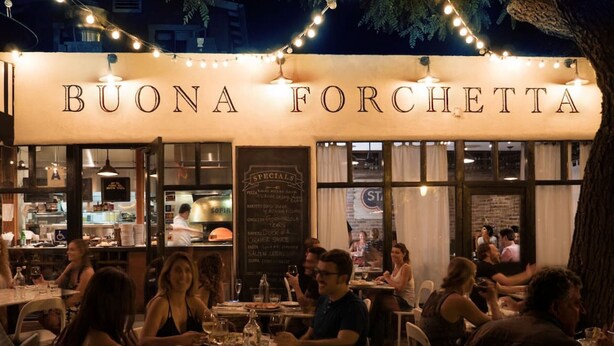 An outdoor dining area of Buona Forchetta restaurant with string lights and patrons seated at tables. - Boutique South Park Craftsman Studio (San Diego)
