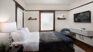 A bedroom with a bed, bedside table, lamp, and a desk with a chair. - Boutique South Park Craftsman Studio (San Diego)