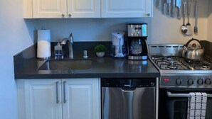 A modern kitchen with white cabinets, stainless steel appliances, and a gas stove. - Boutique South Park Craftsman Studio (San Diego)