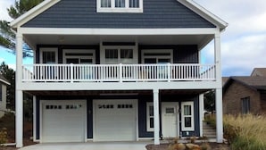 Une maison à deux étages avec un balcon, deux garages et une porte d’entrée.