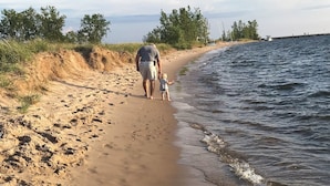 Une plage de sable où une personne et un enfant se promènent le long du rivage.