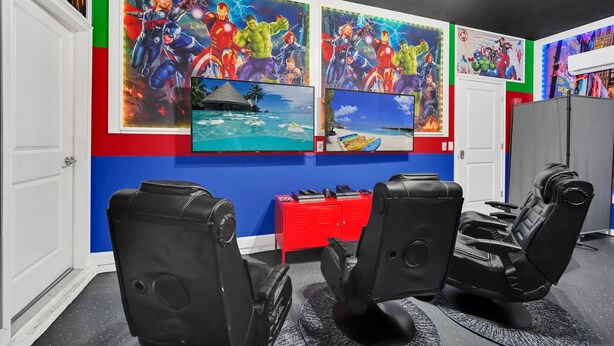 A room with two reclining chairs, a red storage unit, and walls decorated with superhero-themed artwork.