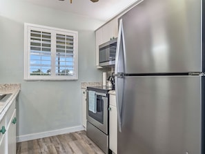 A compact kitchen with a stainless steel refrigerator, a microwave, and a stove. - Spanish Cay by Dream Vacation Rentals (Sanibel)