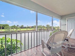 A balcony with wicker chairs, a view of a water body, and a grassy landscape. - Spanish Cay by Dream Vacation Rentals (Sanibel)