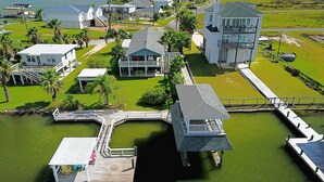 A waterfront property with a dock, a house with a balcony, and a large building with multiple floors.