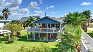 A single-story house with a blue roof and white exterior, featuring a covered porch with outdoor furniture.