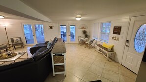 A modern living room with a black leather sofa, a coffee table, and a dining area with a bench and chairs.