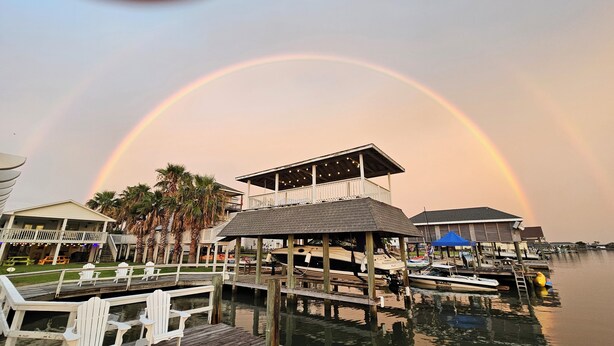 A waterfront property with a dock, boats, and a building with a covered area.