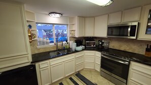 A kitchen with white cabinets, a black countertop, a stainless steel oven, and a microwave.