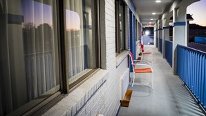 En gang med række af vinduer, blåt gelænder og en bænk.
