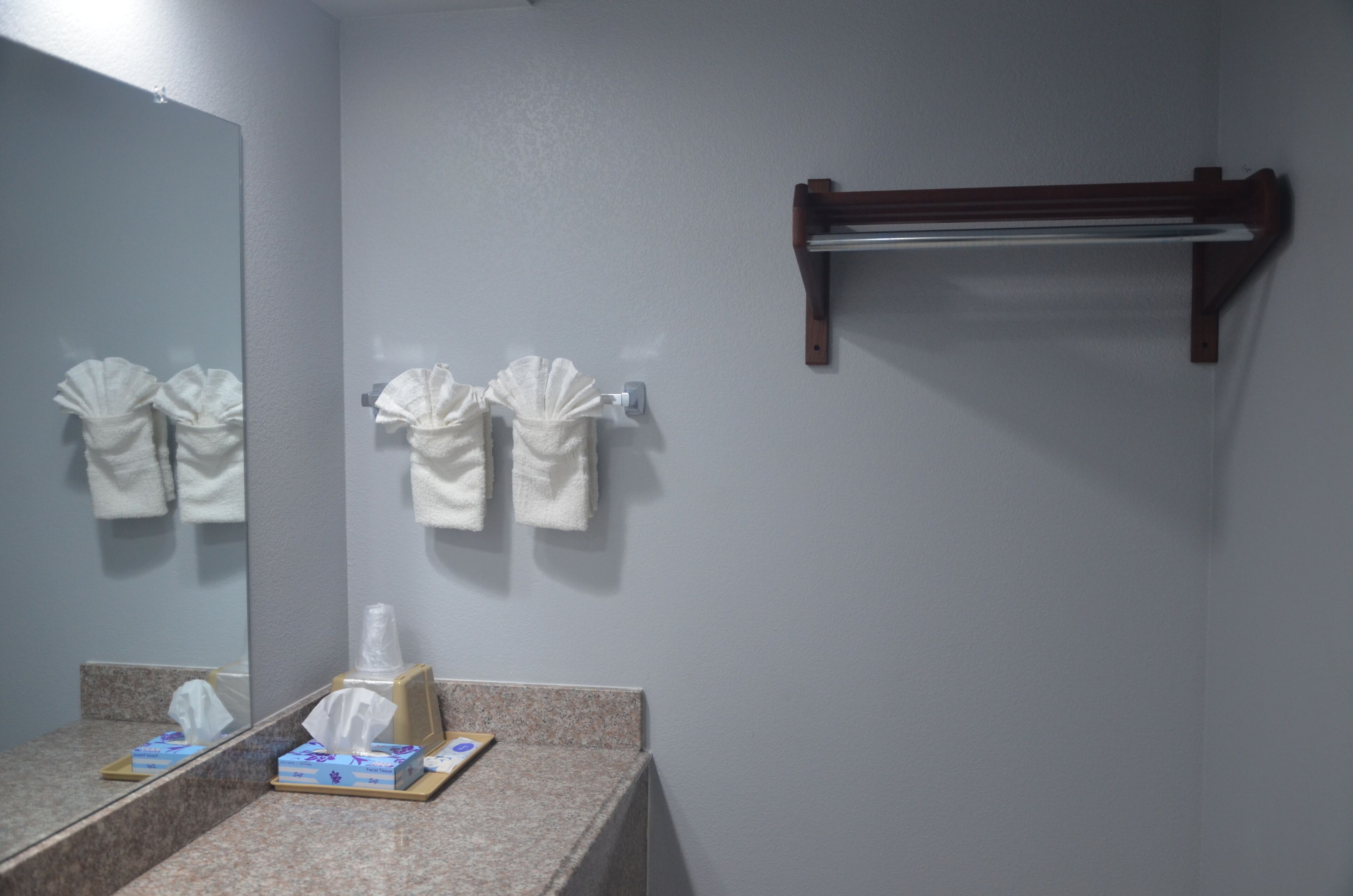 A bathroom with a mirror, towel rack, and a soap dispenser.