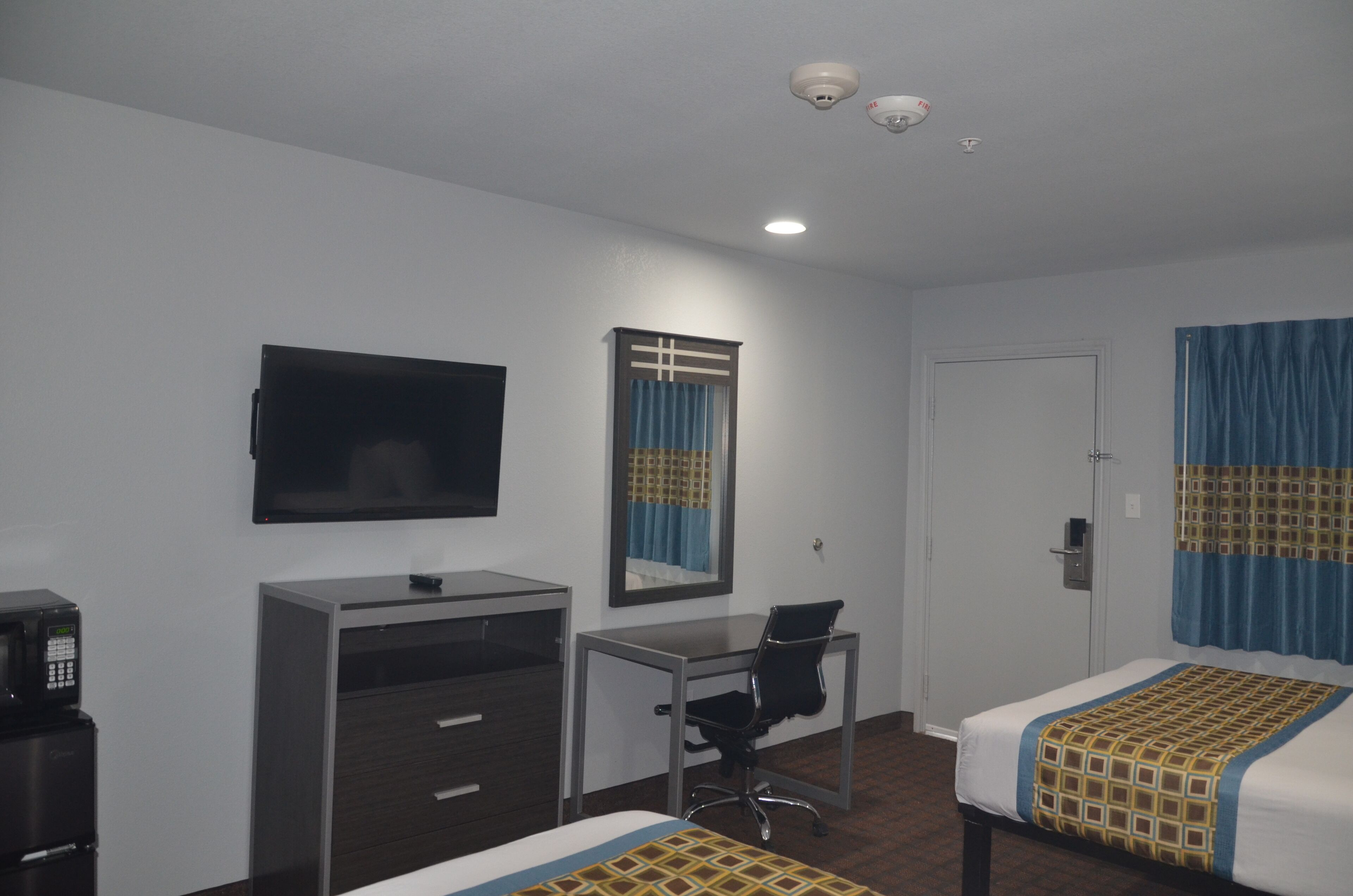 A hotel room with a bed, a desk, a chair, a television, and a wardrobe.