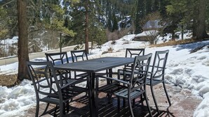A table and chairs set outdoors with a snowy landscape and trees in the background. - Traveler's Mountain Retreat w/ Grotto Cave Room (Idaho Springs)