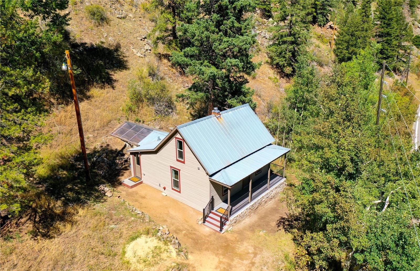 Une maison de plain-pied avec un toit en métal, un petit porche et un panneau solaire sur le toit.