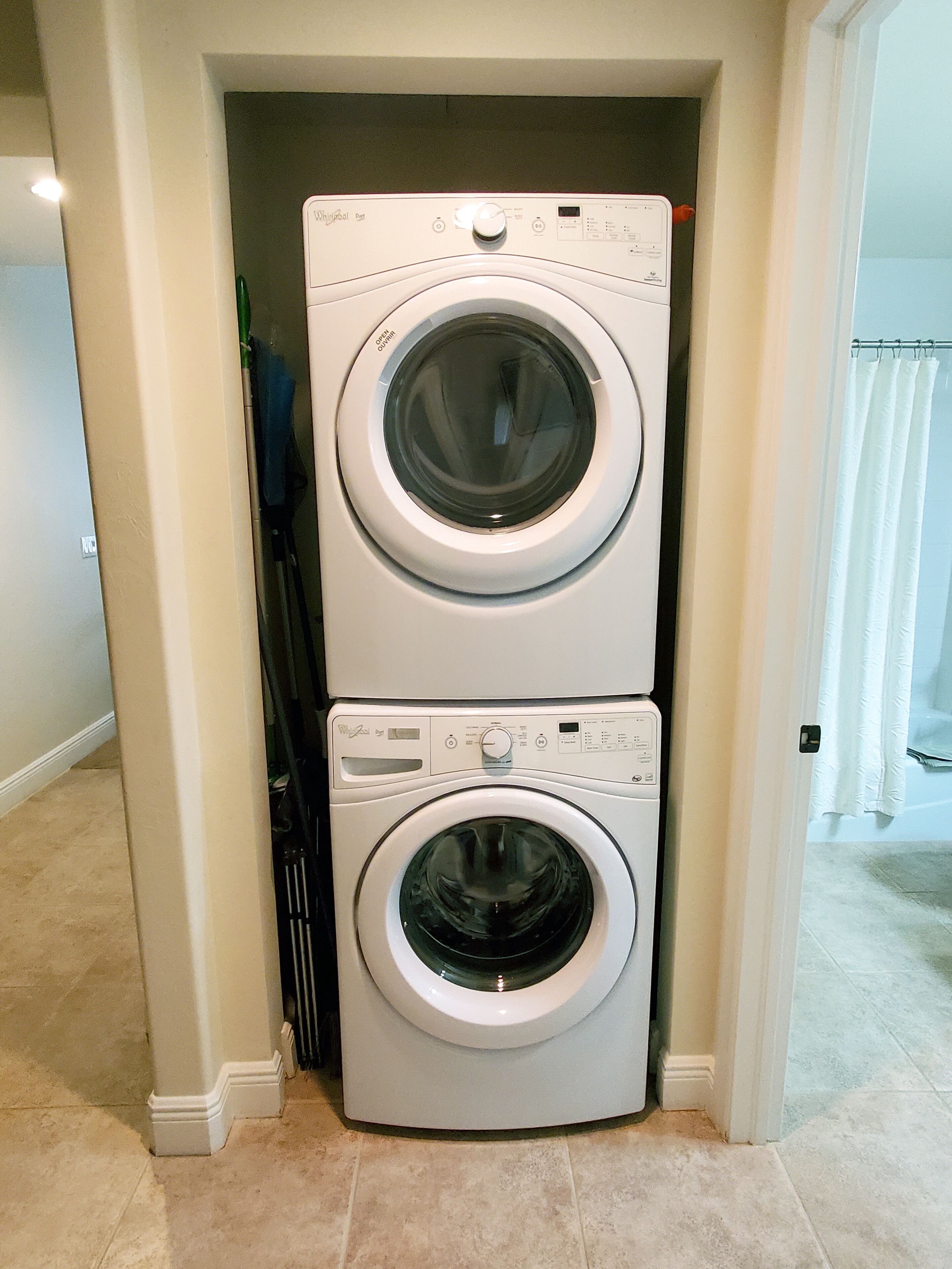 Une machine à laver et un sèche-linge superposés, installés dans un couloir.