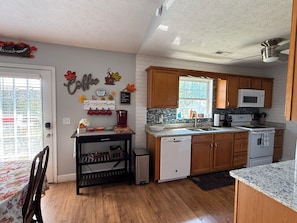 A kitchen with wooden cabinets, a white dishwasher, a microwave, and a coffee station with mugs and a coffee maker. - Central Smoky Mountain Home, 20 Minutes to Knoxville & Pigeon Forge (Seymour)