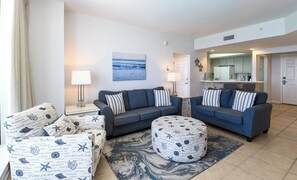 Un salon avec deux canapés, une table basse et un pouf à motifs.