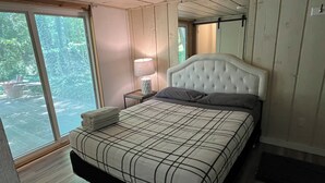 Un dormitorio con una cama, una mesita de noche, una lámpara y una ventana con vistas.