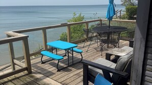 Una terraza de madera con muebles de exterior, incluyendo una mesa y sillas, con vistas a una masa de agua.