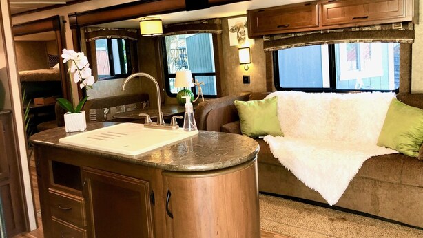 A compact RV interior with a kitchenette, a dining area, and a seating space. - Cactus Camper has lake views with dock & lake access (Spicewood)