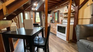 A cozy kitchen with wooden beams, a dining table, and a gray sofa.