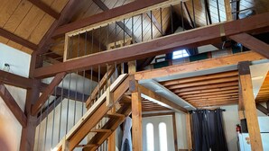 A wooden interior with a staircase, a door with windows, and a table.