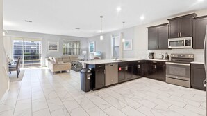 A modern kitchen with dark cabinets, a central island, and stainless steel appliances. - New Listing! Champions Gate Resort, 10mi to Disney & 21mi to Universal - FS272196 (Davenport)