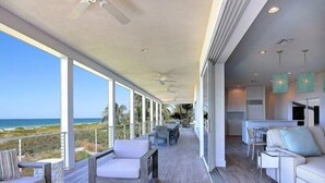 Un balcón amplio con vistas al océano, amueblado con un sofá, sillas y una mesa.
