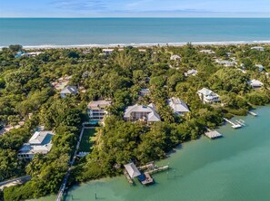 An aerial view of a coastal residential area with houses surrounded by dense greenery and a marina with docked boats. - Bougainvillea Home (Captiva)
