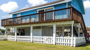 A two-story house with a balcony, a covered porch, and a white picket fence. - The Shell Shack (Galveston)