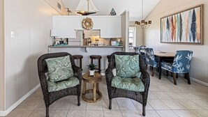 A dining area with wicker chairs, a round wooden table, and a chandelier. - The Shell Shack (Galveston)