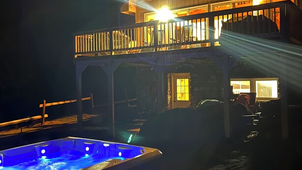Un edificio de dos pisos con balcón y jacuzzi en la parte frontal.